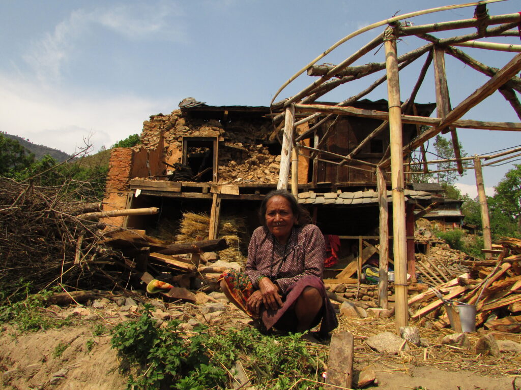 Old women sitting in front of her broken house , She lives alone their with her children in foreign employment and husband dead